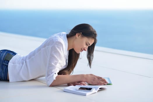 beautiful young woman relax and work on laptop computer while listening music on heaphones and read book at home