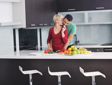 happy young couple have fun in  modern kitchen indoor  while preparing fresh fruits and vegetables food salad