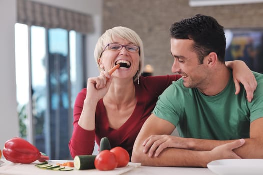 happy young couple have fun in  modern kitchen indoor  while preparing fresh fruits and vegetables food salad