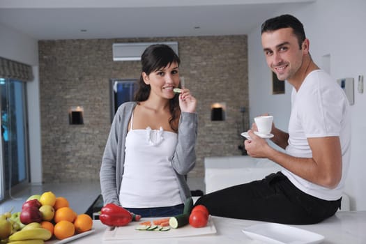 happy young couple have fun in  modern kitchen indoor  while preparing fresh fruits and vegetables food salad