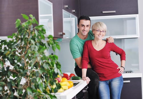 happy young couple have fun in  modern kitchen indoor  while preparing fresh fruits and vegetables food salad