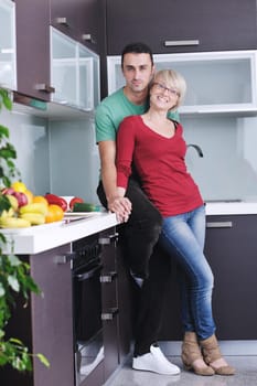 happy young couple have fun in  modern kitchen indoor  while preparing fresh fruits and vegetables food salad