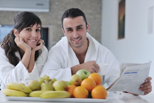 young family couple read newspaper at kitchen in morning with  fresh breakfast  fruits food and coffee drink on table