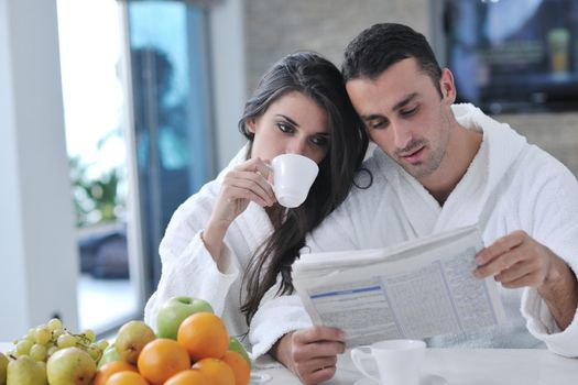 young family couple read newspaper at kitchen in morning with  fresh breakfast  fruits food and coffee drink on table