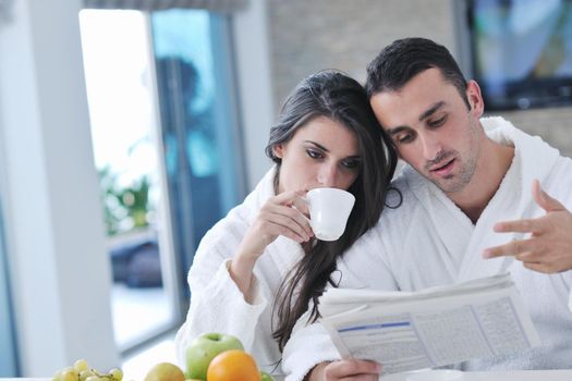 young family couple read newspaper at kitchen in morning with  fresh breakfast  fruits food and coffee drink on table