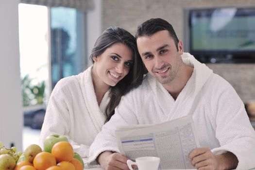 young family couple read newspaper at kitchen in morning with  fresh breakfast  fruits food and coffee drink on table