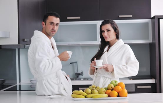 happy young couple have fun in  modern kitchen indoor  while preparing fresh fruits and vegetables food salad