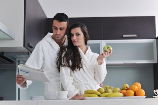 happy young couple have fun in  modern kitchen indoor  while preparing fresh fruits and vegetables food salad