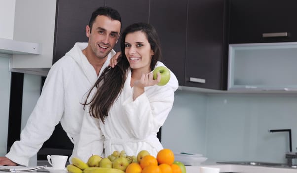 happy young couple have fun in  modern kitchen indoor  while preparing fresh fruits and vegetables food salad