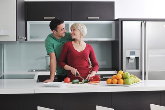 happy young couple have fun in  modern kitchen indoor  while preparing fresh fruits and vegetables food salad