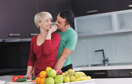 happy young couple have fun in  modern kitchen indoor  while preparing fresh fruits and vegetables food salad