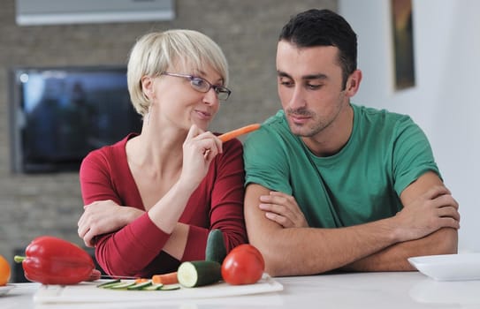 happy young couple have fun in  modern kitchen indoor  while preparing fresh fruits and vegetables food salad