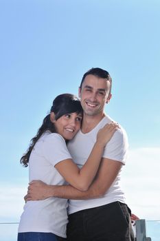 happy young couple relax on balcony outdoor with ocean and blue sky in background