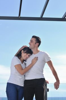 happy young couple relax on balcony outdoor with ocean and blue sky in background