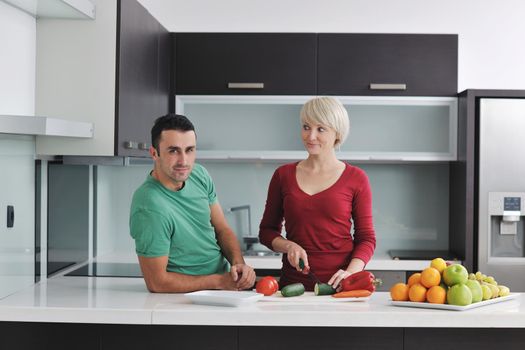 happy young couple have fun in  modern kitchen indoor  while preparing fresh fruits and vegetables food salad