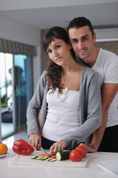 happy young couple have fun in  modern kitchen indoor  while preparing fresh fruits and vegetables food salad