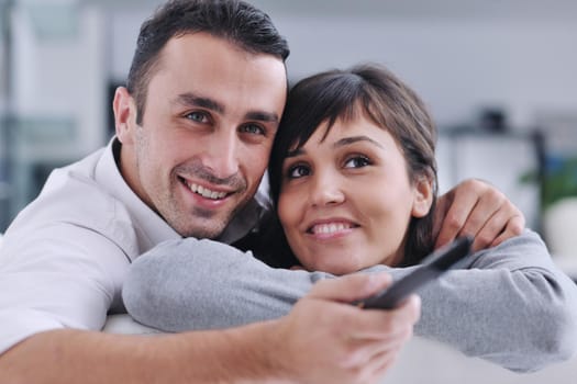 Relaxed young  couple watching tv at home in bright living room