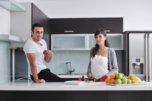 happy young couple have fun in  modern kitchen indoor  while preparing fresh fruits and vegetables food salad