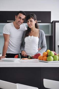 happy young couple have fun in  modern kitchen indoor  while preparing fresh fruits and vegetables food salad