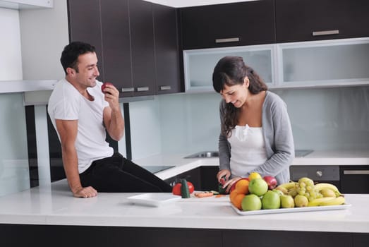 happy young couple have fun in  modern kitchen indoor  while preparing fresh fruits and vegetables food salad