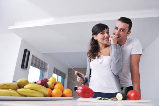 happy young couple have fun in  modern kitchen indoor  while preparing fresh fruits and vegetables food salad