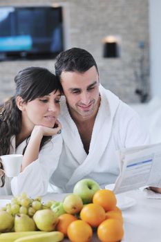 young family couple read newspaper at kitchen in morning with  fresh breakfast  fruits food and coffee drink on table