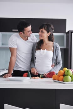 happy young couple have fun in  modern kitchen indoor  while preparing fresh fruits and vegetables food salad