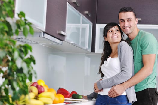 happy young couple have fun in  modern kitchen indoor  while preparing fresh fruits and vegetables food salad