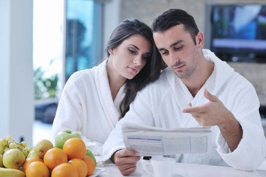 young family couple read newspaper at kitchen in morning with  fresh breakfast  fruits food and coffee drink on table