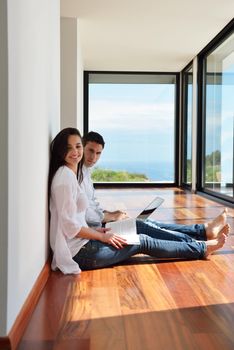 happy young relaxed  couple working on laptop computer at modern home indoor