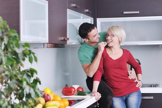 happy young couple have fun in  modern kitchen indoor  while preparing fresh fruits and vegetables food salad