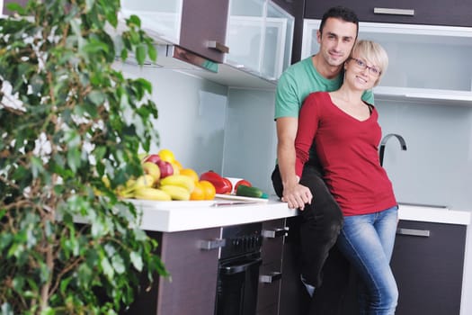 happy young couple have fun in  modern kitchen indoor  while preparing fresh fruits and vegetables food salad