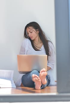 beautiful young woman relax and work on laptop computer while listening music on heaphones and read book at home