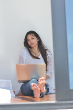 beautiful young woman relax and work on laptop computer while listening music on heaphones and read book at home