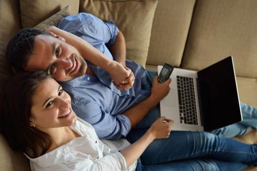 happy young relaxed  couple working on laptop computer at modern home indoor