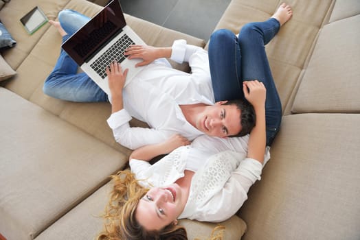 happy young relaxed couple working and playing on laptop computer at home