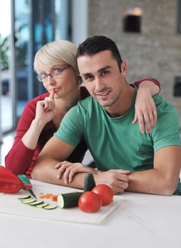 happy young couple have fun in  modern kitchen indoor  while preparing fresh fruits and vegetables food salad