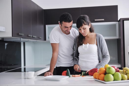 happy young couple have fun in  modern kitchen indoor  while preparing fresh fruits and vegetables food salad