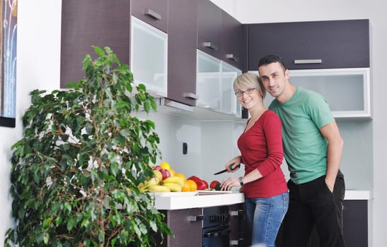 happy young couple have fun in  modern kitchen indoor  while preparing fresh fruits and vegetables food salad