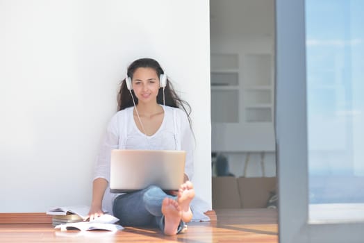 beautiful young woman relax and work on laptop computer while listening music on heaphones and read book at home