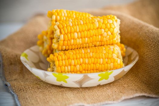 a few heads of boiled corn on a plate on the table