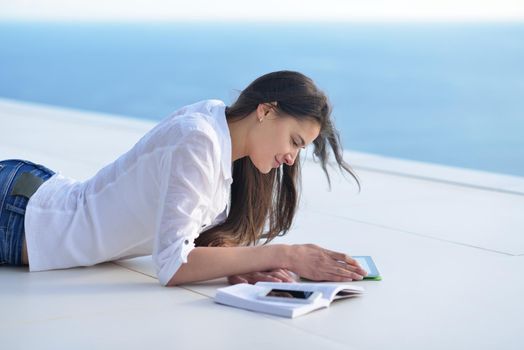 beautiful young woman relax and work on laptop computer while listening music on heaphones and read book at home