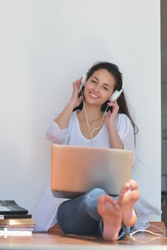 beautiful young woman relax and work on laptop computer while listening music on heaphones and read book at home