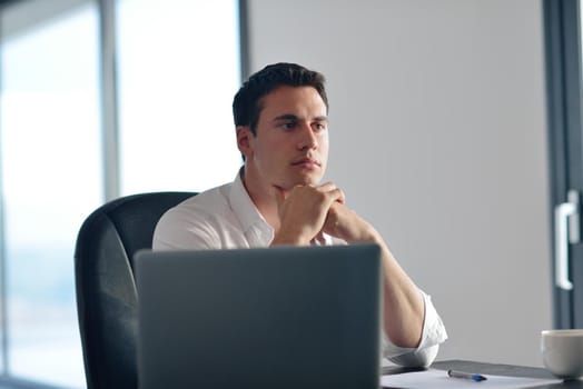 portrait of young happy business man working on laptop computer at home