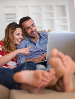 happy young relaxed  couple working on laptop computer at modern home indoor