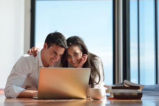 happy young relaxed  couple working on laptop computer at modern home indoor