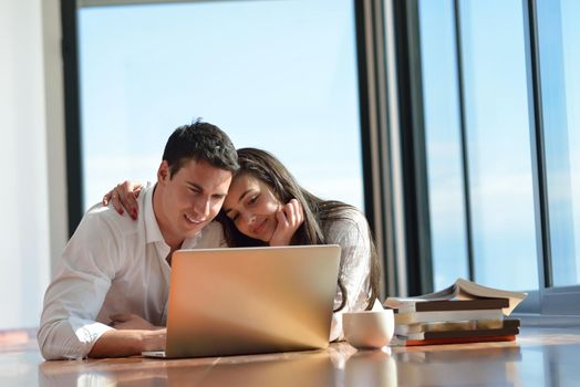 happy young relaxed  couple working on laptop computer at modern home indoor