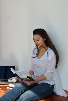 beautiful young woman relax and work on laptop computer while working on laptop computer and read book at home