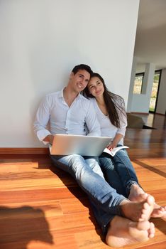 happy young relaxed  couple working on laptop computer at modern home indoor