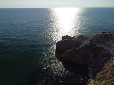 Sea landscape with rocky coastline on sunset time with cloudy sky. Yachts in the Sea on a background of rocky shores. The concept of perfect place for summer travel and rest.
